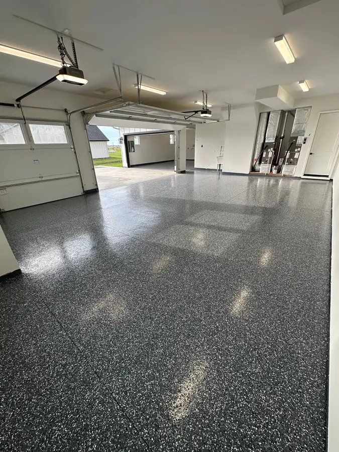 Glossy gray flake floor in a large garage with the doors open